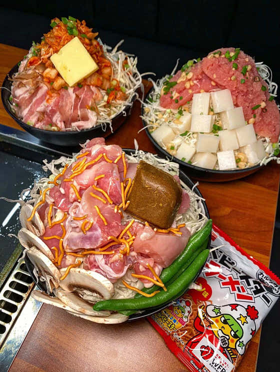Three monjayaki ingredient portions on a griddle at Omonja Yeonnam