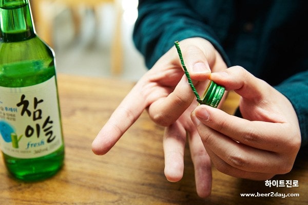 3. 가위, 바위, 보로 순서를 정하고 시계방향으로 한번씩 소주 병뚜껑 꼬리부분을 손가락으로 튕겨친다.
