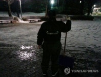 어둠 속 제설 작업하는 공원관리인