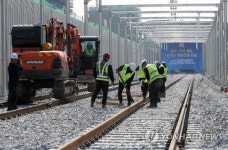 마지막 레일 연결하는 공사 관계자들
