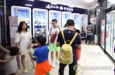 은행 자동화기기 코너에서 더위 피하는 관광객