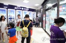 은행 자동화기기 코너에서 더위 피하는 관광객