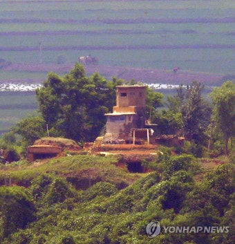 북한 초소 뒤로 보이는 북 주민과 마차