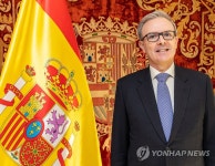 스페인 국기 앞에 선 주한 스페인 대사