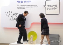 발로 밟는 우산 건조기 시연하는 윤석열 대통령