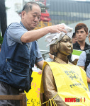 비에 젖은 평화비 소녀상 닦는 시민