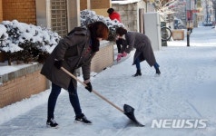 상가 앞 인도에 쌓인 눈 치우는 시민
