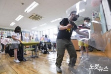 책상 위 가림판 제거하는 초등학생들