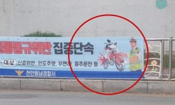 ‘민중은 개·돼지’ 재연?…‘오토바이 타는 개’ 단속 경찰 현수막