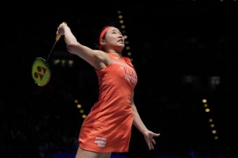 웅장한 닝보 올림픽 스포츠 센터 전경과 셔틀콕을 응시하며 서브를 준비하는 안세영 선수의 강렬한 모습