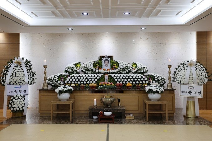 Gia quyến mặc trang phục tang lễ truyền thống (áo liệm) và hiện đại (vest đen).