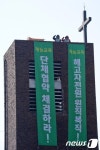 종탑 위에서 구호 외치는 재능교육 해고노동자들