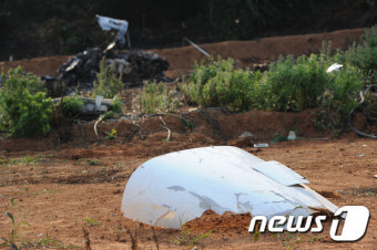 파편 뒤로 보이는 경비행기 추락 사고 현장