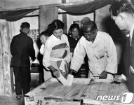 1948년 어린 아이를 업고 투표하는 여인과 할아버지