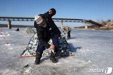 파괴된 다리 아래 저수지서 낚시하는 우크라 주민