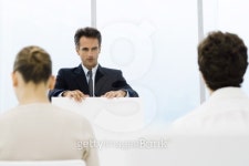 Businessman speaking from lectern, colleagues sitting in... Businessman speaking from lectern, colleagues sitting in foreground