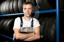 Young mechanic standing next to tire shelves in auto store... Young mechanic standing next to tire shelves in auto store