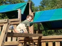 Boy Looking Back Crawling Over Wooden Playground Equipment... Boy Looking Back Crawling Over Wooden Playground Equipment