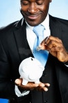 Businessman happily adding coin to piggybank smiles 이미지 (180755008) - 게티이미지뱅크 Businessman happily adding coin to... 