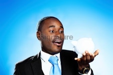 Black businessman looking at piggybank, surprised 이미지 (187104612) - 게티이미지뱅크 Black businessman looking at piggybank... 
