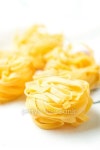 Nests of dry pasta tagliatelle on tablecloth vertical 이미지... Nests of dry pasta tagliatelle on tablecloth vertical