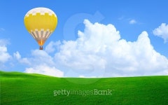 Hot air balloon floating in the sky over green grass 이미지... Hot air balloon floating in the sky over green grass
