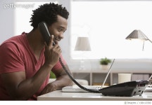 108113390 | 게티이미지코리아 | Smiling Black man talking on telephone in home office Royalty-Free 이미지