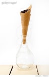 700862941 | 게티이미지코리아 | Close-Up Of Roasted Coffee Beans In Brown Paper In Glass Vase On Table Against White Background... 