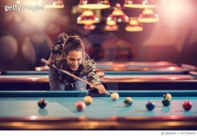 667380818 | 게티이미지코리아 | Smiling woman enjoying while playing billiard in a pub. Royalty-Free 이미지