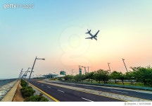 667939688 | 게티이미지코리아 | An airplane flying down over the expressway under the sunset sky Royalty-Free 이미지