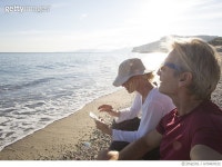 670467632 | 게티이미지코리아 | Couple relax at beach edge, woman sends text Rights-Managed 이미지