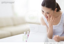 LARF17000726 | 게티이미지코리아 | Woman looking at self in mirror and touching face Royalty-Free 이미지