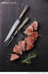 696670520 | 게티이미지코리아 | Sliced medium rare Roast beef with table knife and fork for meat on dark background Royalty-Free... 