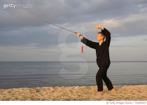 730289925 | 게티이미지코리아 | Mature Man Practicing Tai Chi With Sword At Beach Against Cloudy Sky Royalty-Free 이미지