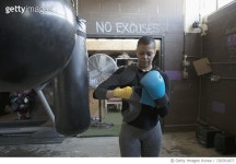 728761877 | 게티이미지코리아 | Female boxer putting on boxing gloves at punching bag in gritty gym Royalty-Free 이미지
