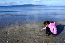 695712064 | 게티이미지코리아 | Young girl drawing in the sand on a beach Royalty-Free 이미지
