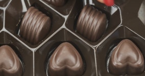 Box of chocolate bonbon candies put on a table and hands taking... chocolate bonbon candies put on a table and hands taking... 