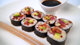 Sticks taking vegetarian sushi from table, Closeup of eating vegan sushi filled with avocado. Sushi restaurant, food delivery.... 