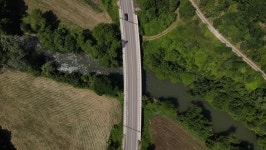Aerial - Drone tracking red car from busy bridge to land. Top view Transportation Videos Aerial - Drone tracking red car from... 