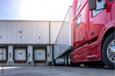 Red modern American semi truck parked at the docks, waiting to get loaded. Shipping and receiving, transportation business... 