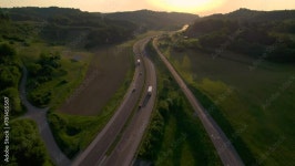 AERIAL, LENS FLARE: Winding motorway that leads through a picturesque countryside of rolling hills and covered with lush green... 