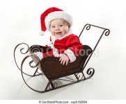 Santa baby sitting in a sleigh. Adorable young baby wearing a santa claus suit and hat sitting in a metal christmas snow | CanStock