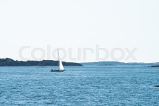 Lonely sailboat crossing a calm bay.. | Stock image | Colourbox