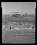[Photograph of UH-1B Iroquois helicopter flying over a city] - UNT Digital Library [Photograph of UH-1B Iroquois helicopter... 