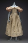 1830, A dress, made of 18th century Spitalfields brocade, wide flaring neckline, short very full puffed sleeves, bodice fitted to... 