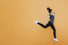 Fit woman jumping at orange wall  Photo | Free Download