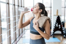 Woman with towel drinking in gym  Photo | Free Download