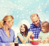 food, family, children, happiness and people concept - happy family with two kids making salad for dinner over blue sky and snowflakes... 