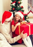 family, christmas, x-mas, winter, happiness and people concept - smiling father and daughter in santa helper hats opening gift box... 