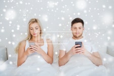 유토이미지 | people, technology, internet addiction and communication concept - couple with smartphones texting in bed over snow